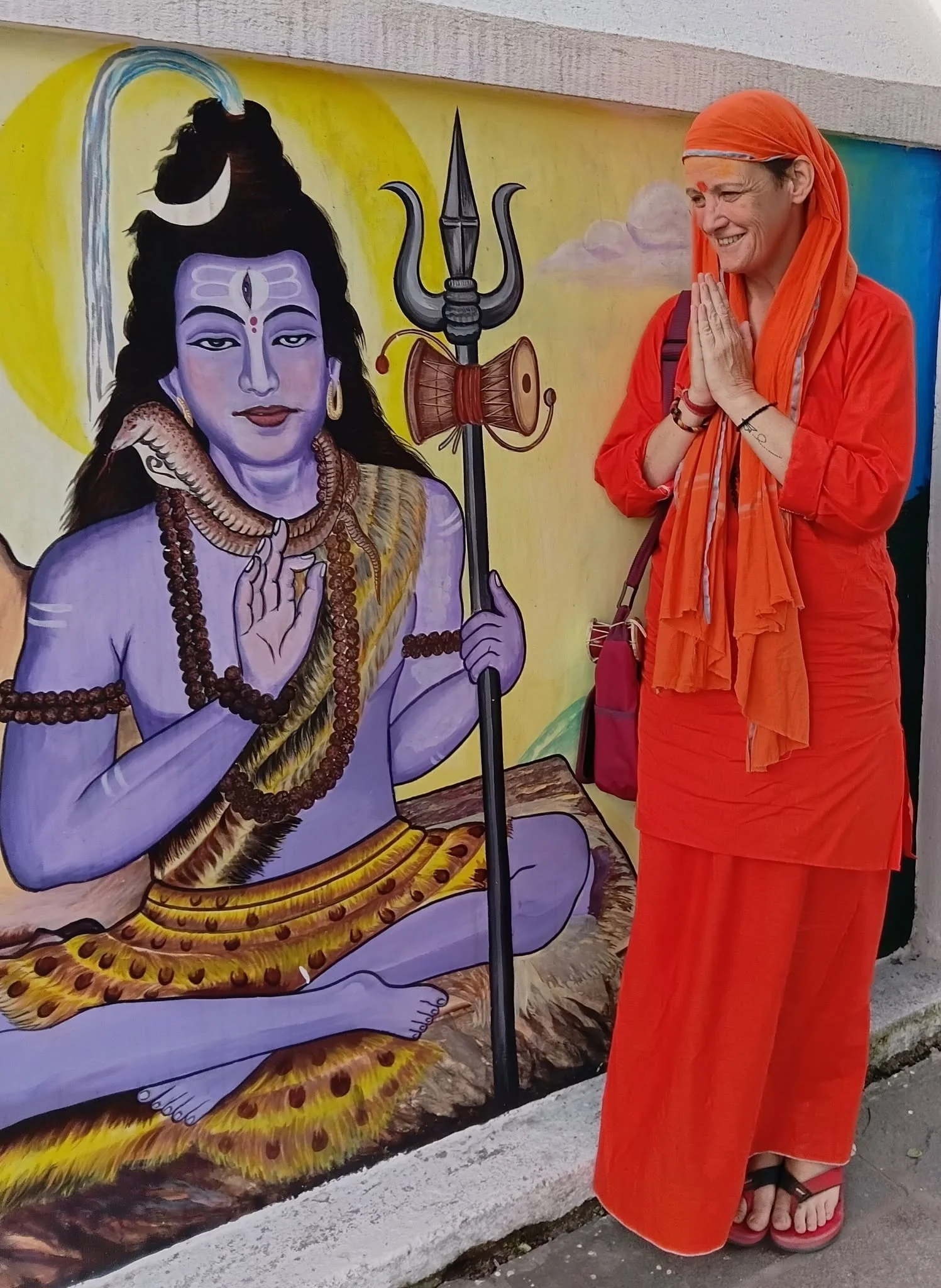 A woman standing beside a painted image of Shiva